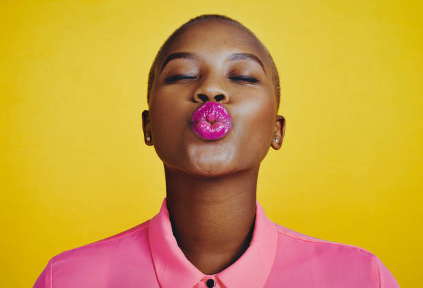 I don't kiss and tell Cropped shot of an attractive young woman kissing and pouting in studio against a yellow background puckering stock pictures, royalty-free photos & images