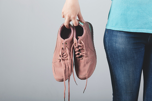 woman hand holding sport shoes on white background