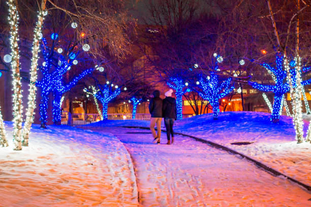 Couple walking through a park lit up for Christmas stock photo
