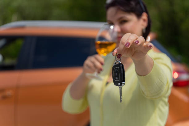 指定されたドライバーの概念。ワインのグラスを持つ女の子は、地味なドライバーに車の鍵を手渡します。キーに焦点を当てます。 - designated driver ストックフォトと画像