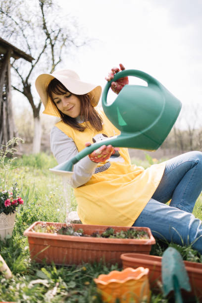 istock Smiling girl watering flowers while sitting on the ground 1223245055