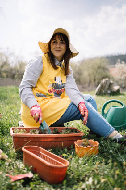 istock Lady looking at camera while planting in the garden 1223245145