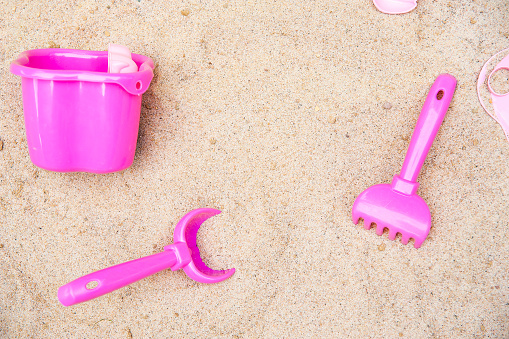 Toy scoop, bucket and rakes in the sand