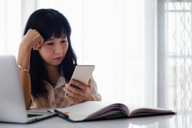 istock Asian woman using smartphone with computer laptop and working at home for business, self-quarantine, staying home and social distancing in coronavirus or Covid-2019 outbreak situation concept 1223245937