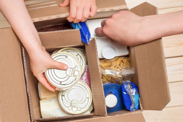 istock Assistance concept at quarantine time because of coronavirus infection Covid-19. Hands opening a food delivery box at home, online ordering. Grocery store delivery. Box of food in donation boxparcel. 1223246830