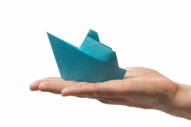 istock Blue paper ship in human palm. 1223249997