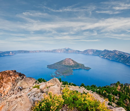 Crater Lake exists in the blown-out caldera of a once mighty volcano known as Mount Mazama. This view of the lake and Wizard Island in the evening was photographed from Watchman Overlook in Crater Lake National Park, Oregon, USA.