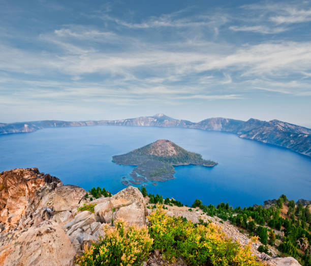 Crater Lake in the Evening Crater Lake exists in the blown-out caldera of a once mighty volcano known as Mount Mazama. This view of the lake and Wizard Island in the evening was photographed from Watchman Overlook in Crater Lake National Park, Oregon, USA. jeff goulden crater lake national park stock pictures, royalty-free photos & images