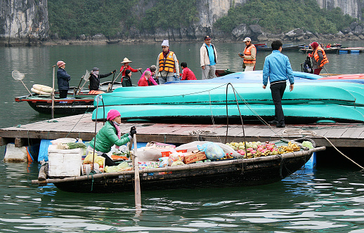 Halong Bay, Vietnam - February 08, 2010: A young Vietnamese woman proudly seats aboard her boat selling fruit from in Halong Bay. The Market is held everyday and has become very popular with tourists visiting Vietnam.