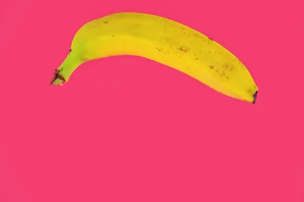 Photo of Yellow banana shape on pink background. Banana Minimal. Pastel colors style. Popart. Digitalart. Surreal. Pop. Creative. Minimalist art. Banana Minimal. Fashion Bananas, Minimalist Fruits, Fashion and Food, Food and Art, fruit Minimalism. Copy space.