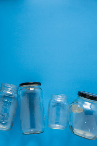 istock Isolated glass jars laid flat on blue background with blank empty room space room for text, copy, or copyspace on top. Recycling program or campaign image with an assortment of top view containers. 1223256020
