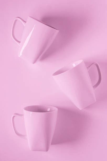 istock 3 monochromatic pink coffee mugs scattered on pink background with blank empty room space for text, copy, or copyspace. Modern top view concept of three several cups with solid background backdrop 1223256076