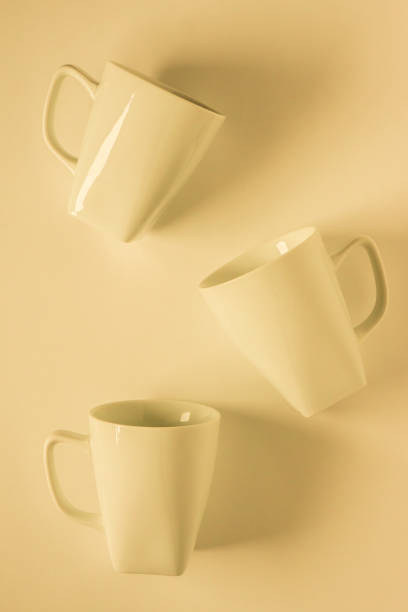 istock 3 monochromatic yellow coffee mugs scattered on yellow background with blank empty room space for text, copy, or copy space. Modern top view concept of three several cups, solid background backdrop 1223256185