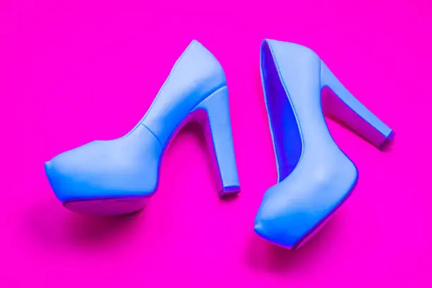 Blue high heeled shoes on pink purple background - top view concept - blank empty room space for text or copy. Classic fashion. Heels walking left. Dress up.