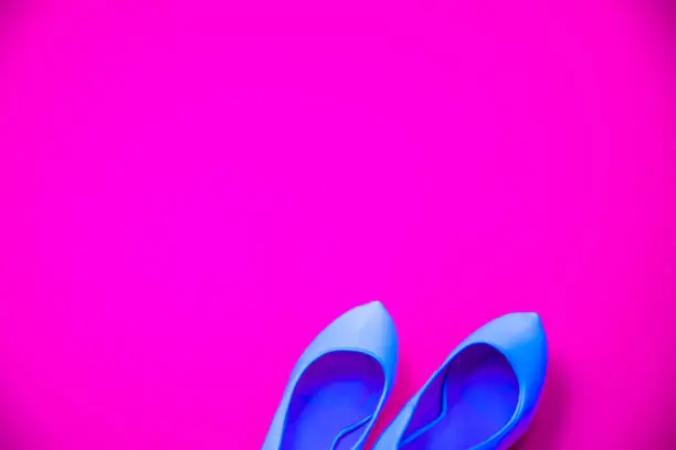 Blue high heeled shoes on pink purple background - top view concept - blank empty room space for text or copy. Classic fashion. Heels pointing right.
