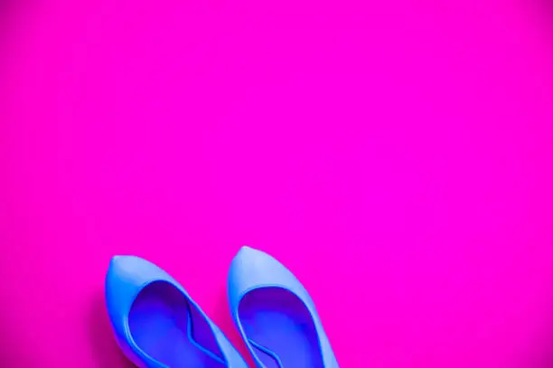 Blue high heeled shoes on pink purple background - top view concept - blank empty room space for text or copy. Classic fashion. Heels pointing left