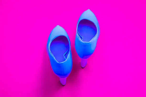 Blue high heeled shoes on pink purple background - top view concept - blank empty room space for text or copy. Classic dress up fashion. Heels pointing up