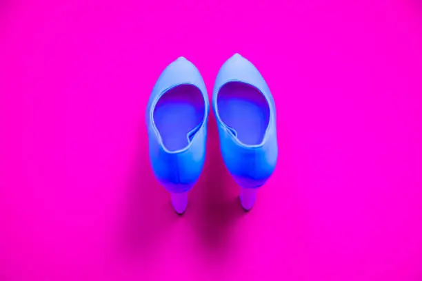 Blue high heeled shoes on pink purple background - top view concept - blank empty room space for text or copy. Classic dress up fashion. Heels pointing up. Dressed up.