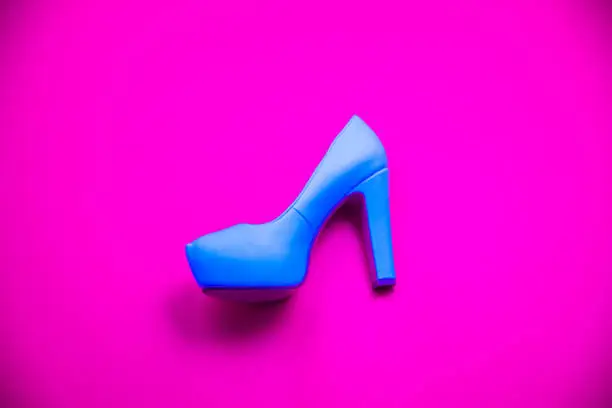 Blue high heeled shoes on pink purple background - top view concept - blank empty room space for text or copy. Classic dress up fashion. Profile of heel