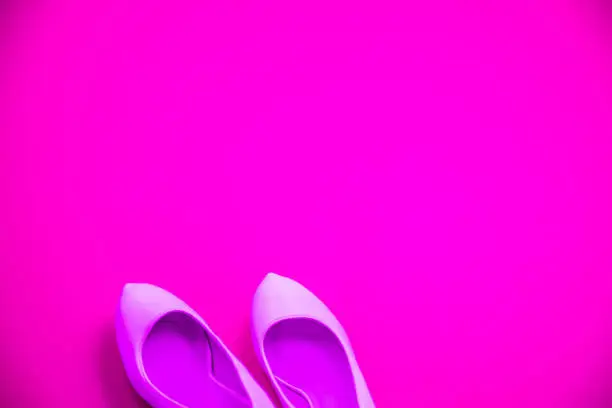 Pink high heeled shoes on pink purple background - top view concept - blank empty room space for text or copy. Suitable for holidays like Valentine's. Classic fashion. Heels pointing left