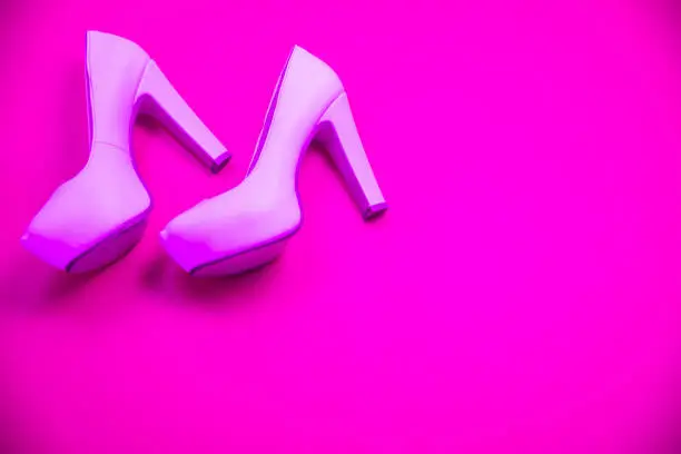 Pink high heeled shoes on pink purple background - top view concept - blank empty room space for text or copy. Suitable for holidays like Valentine's. Classic fashion. Heels walking left.