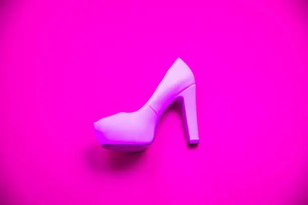 Pink high heeled shoes on pink purple background - top view concept - blank empty room space for text or copy. Suitable for holidays like Valentine's. Classic dress up fashion. Profile of heel