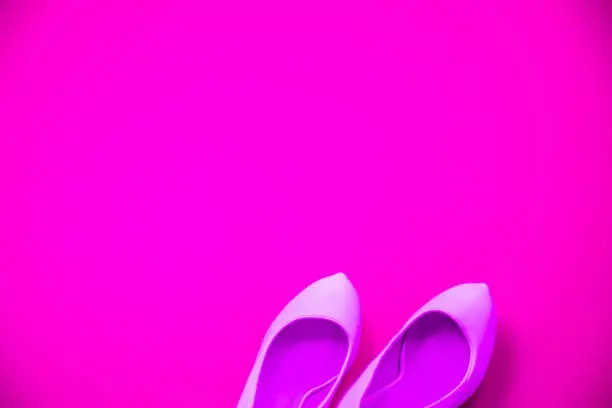 Pink high heeled shoes on pink purple background - top view concept - blank empty room space for text or copy. Suitable for holidays like Valentine's. Classic fashion. Heels pointing right.