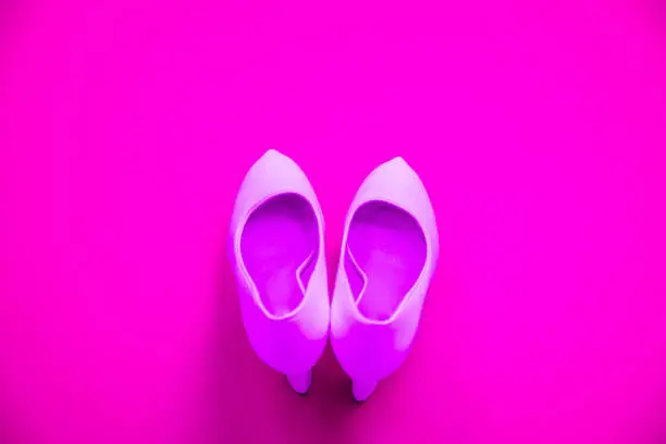 Pink high heeled shoes on pink purple background - top view concept - blank empty room space for text or copy. Suitable for holidays like Valentine's. Classic dress up fashion. Heels pointing up