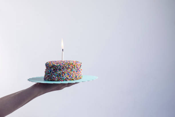 istock Hand holding a small colorful cake in white background 1223258730