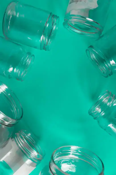 Isolated open glass jars, flat on teal mint green background, blank empty room space room for text, copy, or center copy space. Recycling program or campaign, assortment of top view containers.