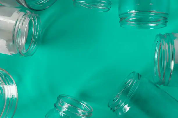 Isolated open glass jars, flat on teal mint green background, blank empty room space room for text, copy, or center copy space. Recycling program or campaign, assortment of top view containers.