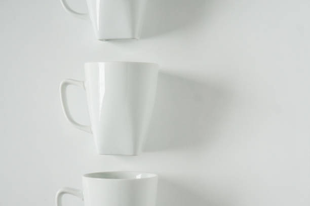istock One singled out monochromatic white coffee mug lined up in a row on white background with blank empty room space for text, copy, or copy space. Modern top view concept with solid background backdrop 1223259128