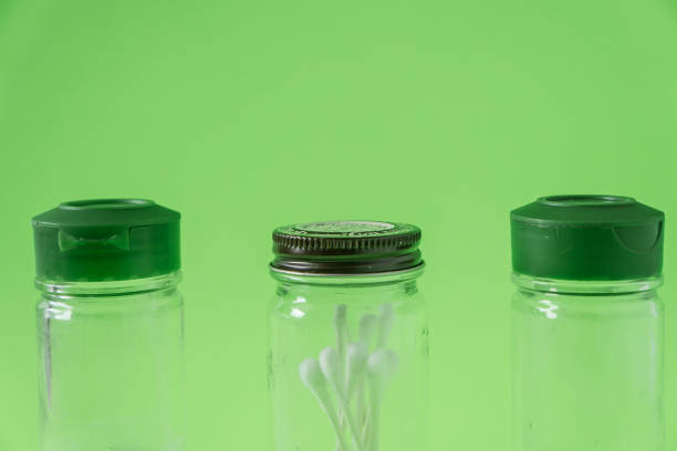 istock 3 Glass spice jars on lime green background with blank empty room space for text or copy. Three kitchen bottles recycled and reused to store cotton swabs bathroom essentials. Recyclable junk garbage. 1223260519
