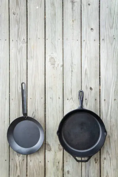 Carbon steel vs cast iron versus teflon pans and skillets - blank empty room for text or copy space on top. Cookware battle comparison comparing healthier kitchen cooking options. Stove to oven.