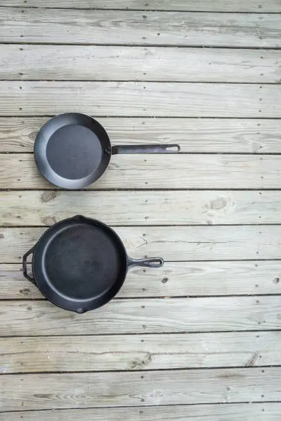 Cookware battle with cast iron vs teflon vs carbon steel skillet pan cooking options - blank empty room for text or copy space on right. Traditional versus new healthier option.