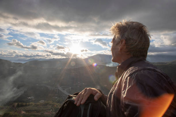 istock Mature man watches the sun rise over distant hillside 1223262309