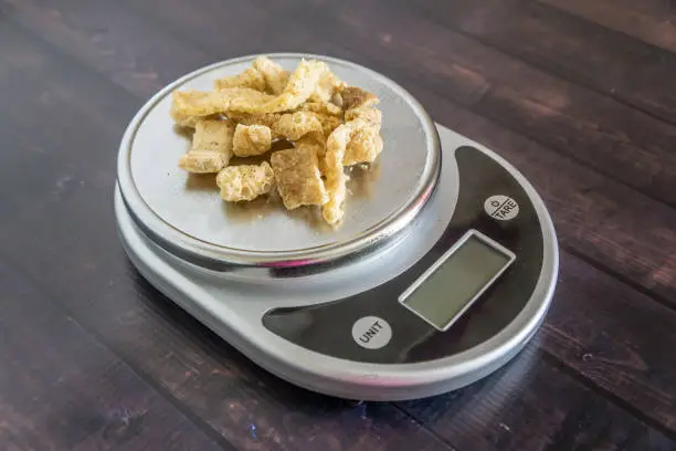 High fat low carb healthy snack - pork rinds measured on kitchen scale. Blank empty room for text or copy space. Keto friendly food for low carbohydrate diet.