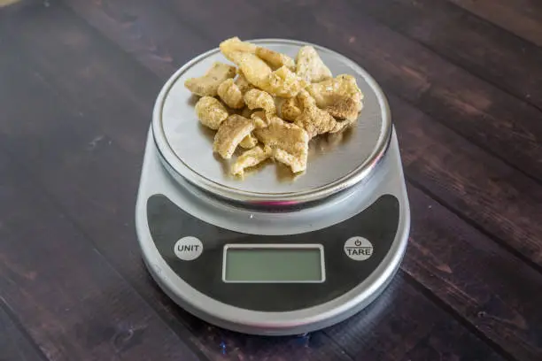 High fat low carb healthy snack - pork rinds measured on kitchen scale. Blank empty room for text or copy space. Keto friendly food for low carbohydrate diet.