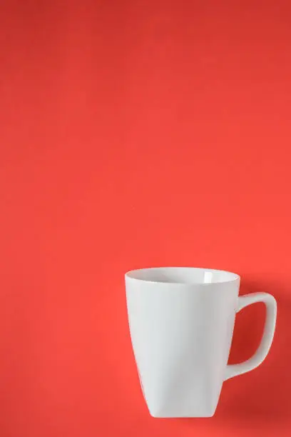 White coffee mug on red background - isolated with copy space above.