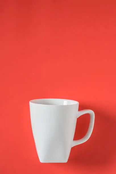 White coffee mug on red background - isolated with copy space above.