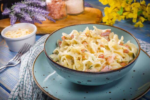 Tagliatelle mosse Carbonara in bowl on wooden table. Shallow depth of field.