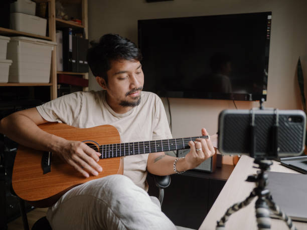 istock Hipster Man Giving Guitar lesson On Internet With Video Tutorial At Home. 1223266738