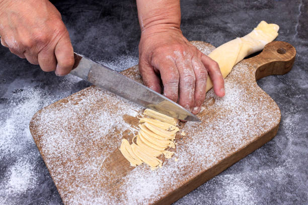 istock Man preparing bread dough on wooden table in a bakery close up 1223267535
