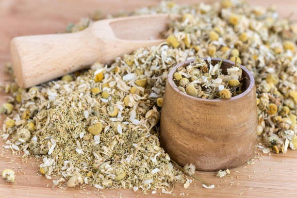 Wooden bowl and measuring spoon in dry chamomile tea stock photo