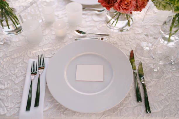 istock Wedding dinner table reception. View from above on white round plates close-up. Bouquets of pink, orange, green flowers. Pink roses, small orange roses. Top view 1223271426