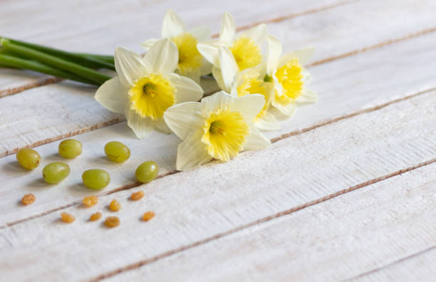 istock Yellow daffodils, pear, grape on white wooden background 1223275516