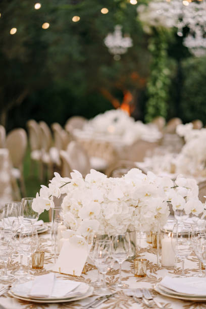 istock Wedding dinner table reception. A large bouquet of white orchids on the table among plates, glasses and candles. Wedding floristry 1223276857