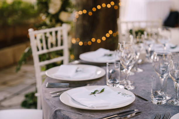 istock Wedding dinner table reception. White round plates on a round table with gray tablecloth, white Chiavari chairs with white pillows. A floral arrangement in the center of the table. 1223278066