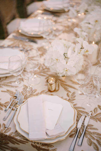 istock Wedding dinner table reception. Delicate creamy pastel tones of tablecloths and plates on table, three forks left and two knives on right, glasses and candles in candlesticks 1223278972