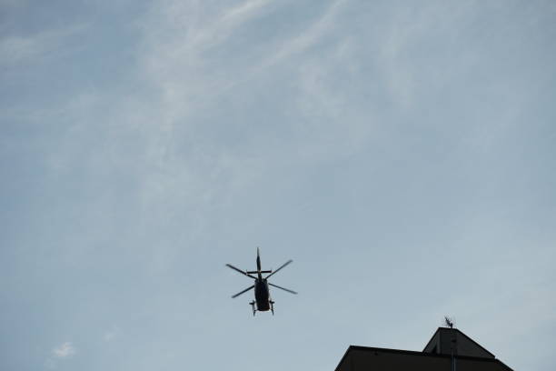istock a helicopter flying above the rooftops with blue, slightly covered sky 1223280175
